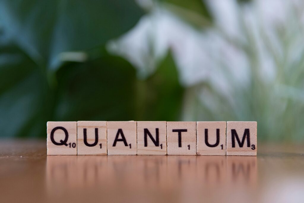 pexels-photo-30901565-30901565 Creative depiction of 'quantum' using wooden letter blocks on a blurred natural background.